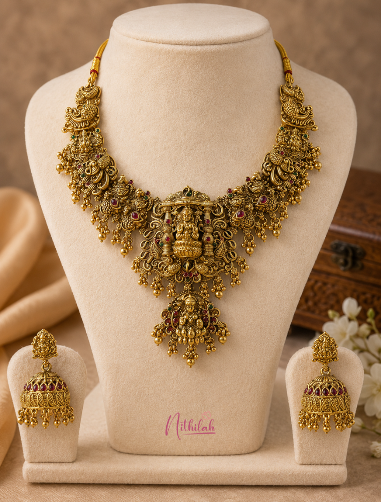 Antique Lakshmi Temple Jewellery Necklace Set with matching jhumka earrings displayed on a black jewellery bust showcasing intricate temple craftsmanship and antique gold finish.