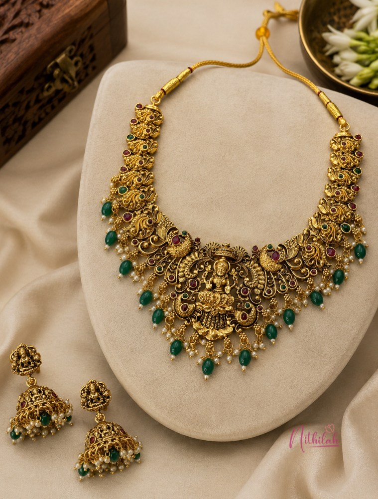 Antique Lakshmi Temple necklace set with green bead drops and matching jhumka earrings displayed in flat lay.