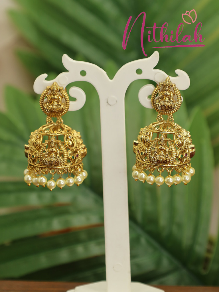 Gold-plated Lakshmi temple jhumka earring with intricate filigree detailing and cream pearl drops, close-up view.
Copy filenameCopy alt text