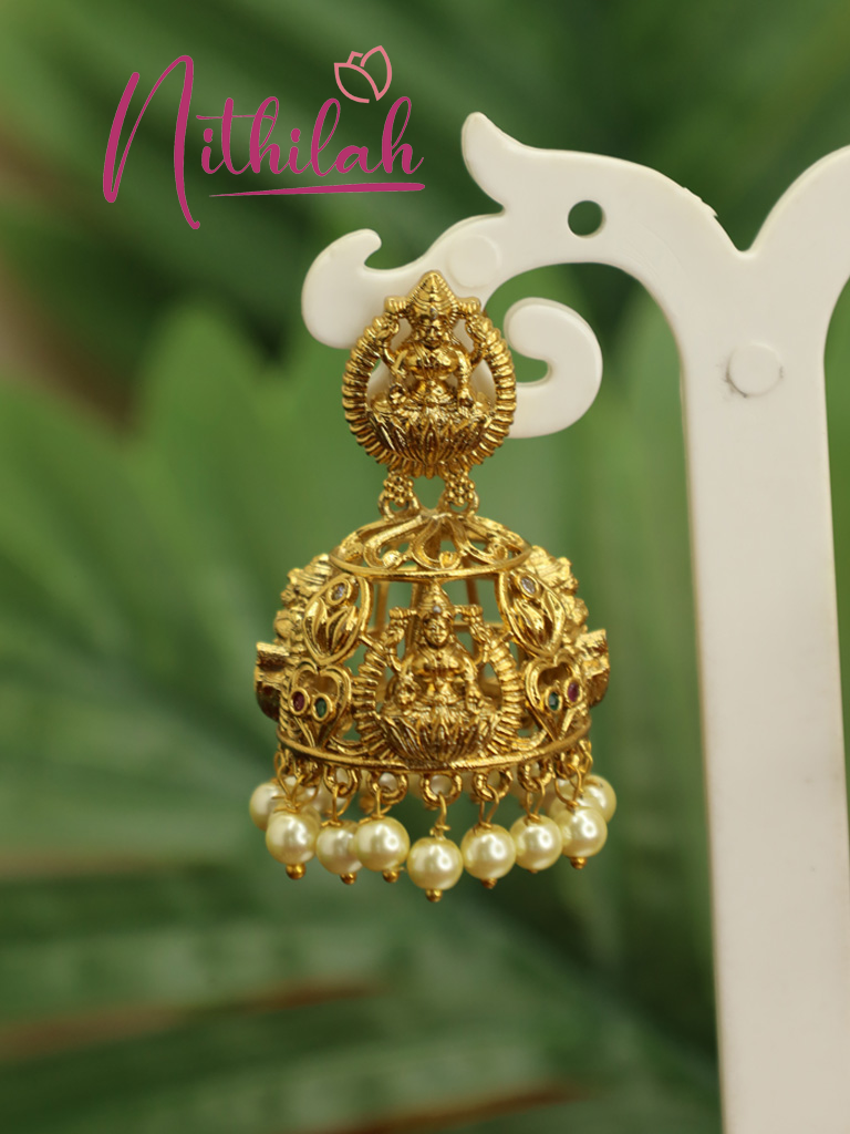 Single gold-plated Lakshmi temple jhumka earring with Goddess Lakshmi motifs and pearl bead fringe displayed on a white stand.