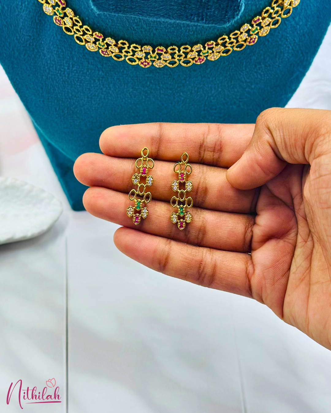 Close-up of gold-plated multicolour CZ oval-link drop earrings held in a hand