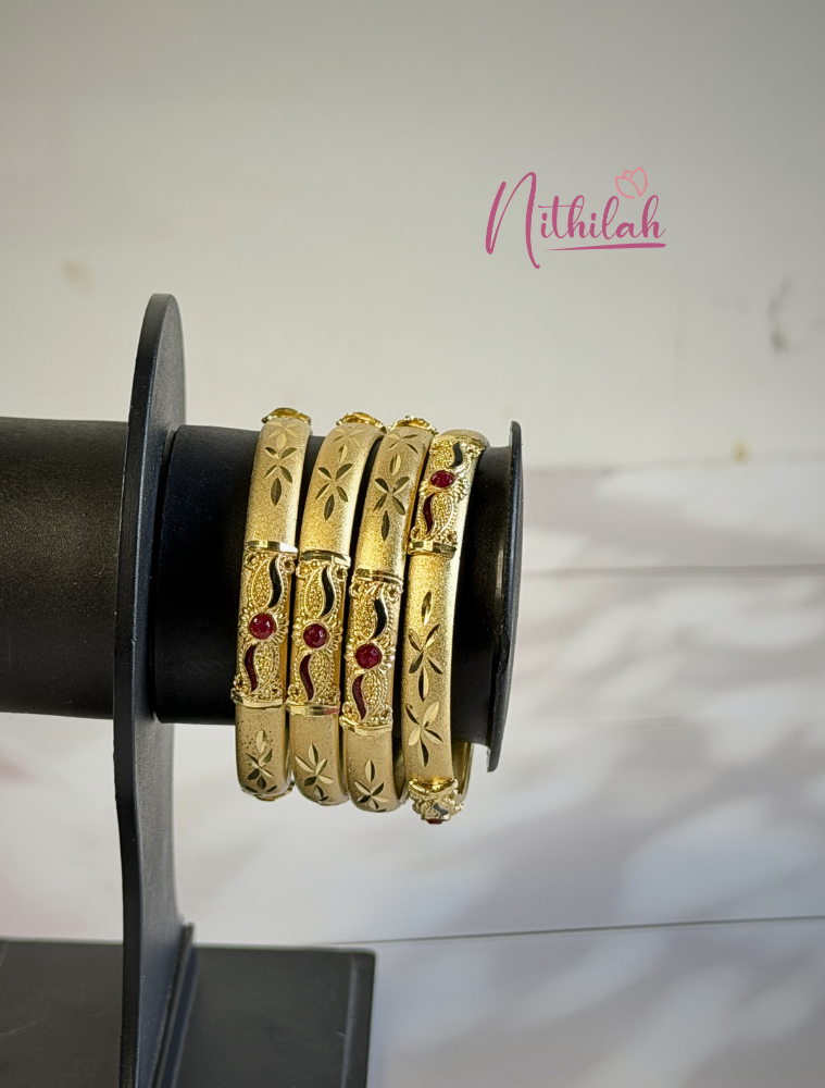 Gold plated traditional kids bangles with ruby stone detailing, matte finish and floral engraved design for girls kept on stand