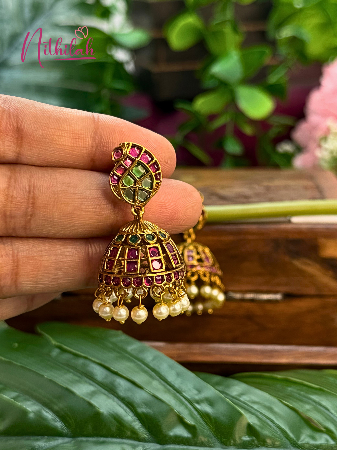 Traditional Kemp stone jhumka earring with pearl drops shown in hand