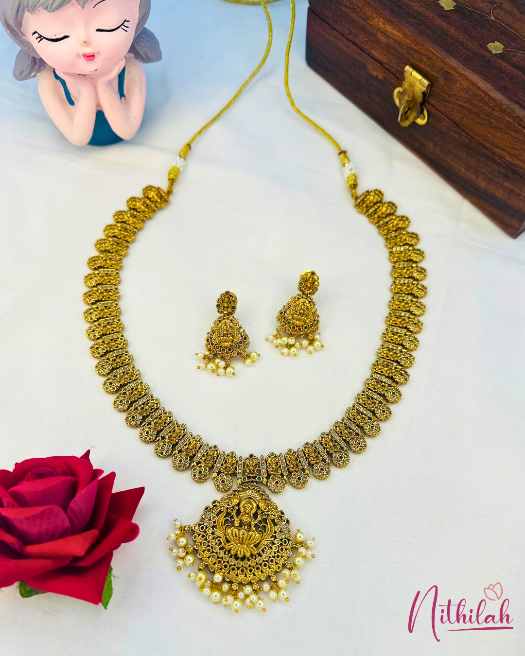 Antique Lakshmi haaram set laid flat, showing the ornate pendant, pearl drops, matching earrings and adjustable thread