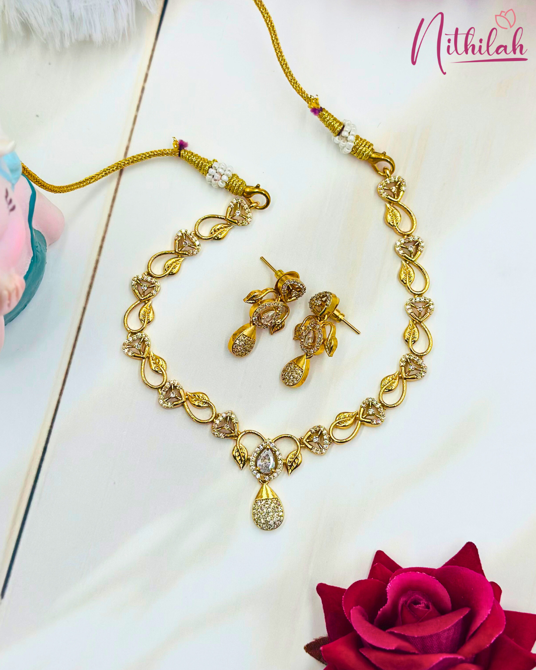 Gold-plated leaf CZ necklace set laid flat, showing triangular stone accents, matching earrings and adjustable thread