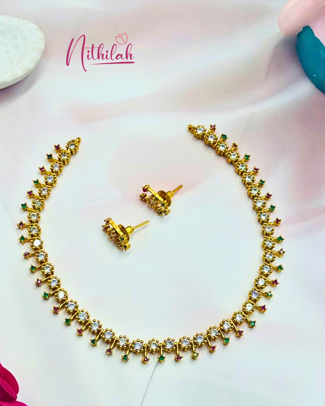 Detailed flat-lay view of the necklace’s clear stones and alternating pink and green accents, with matching earrings