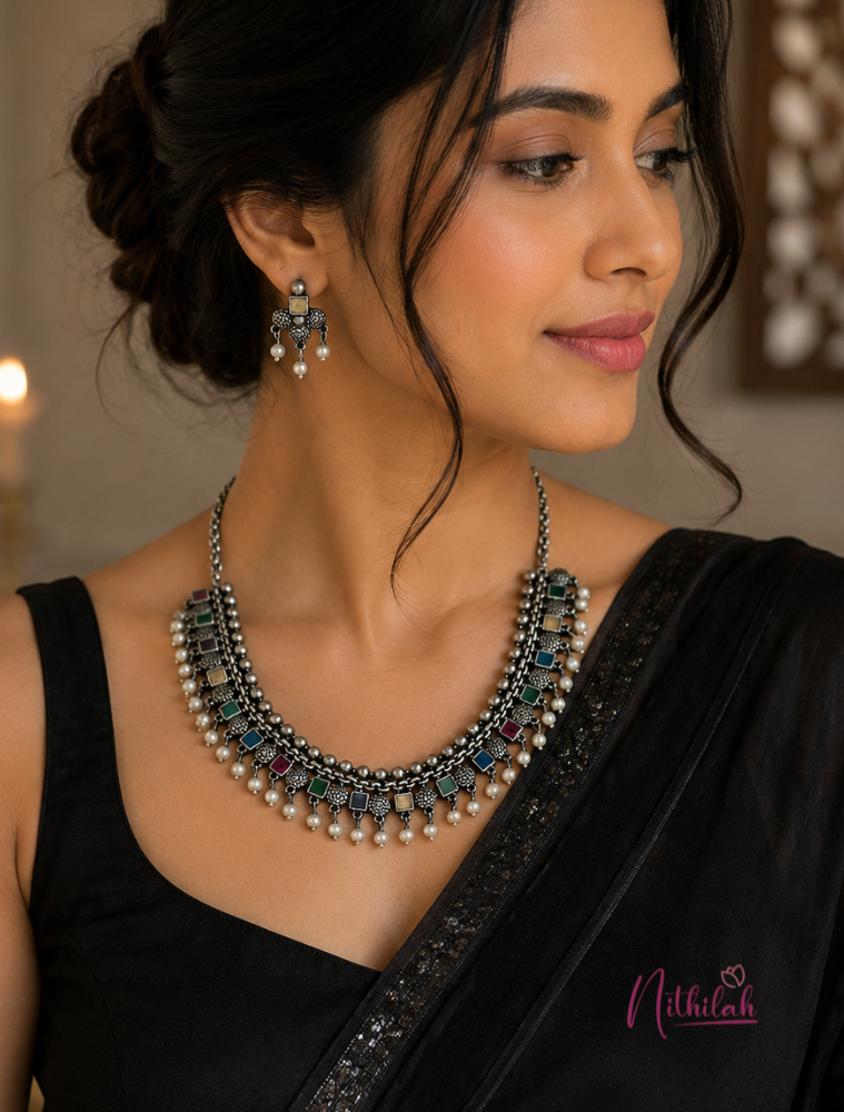 South Indian woman wearing a premium oxidised silver multicolour stone necklace set with matching earrings and a black saree.