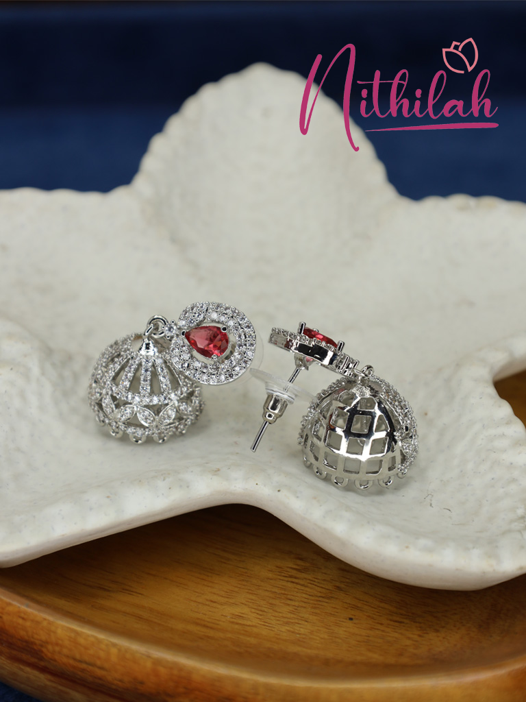 Close-up of silver-tone AD jhumka earrings with red teardrop stones showing the intricate dome design and earring post.