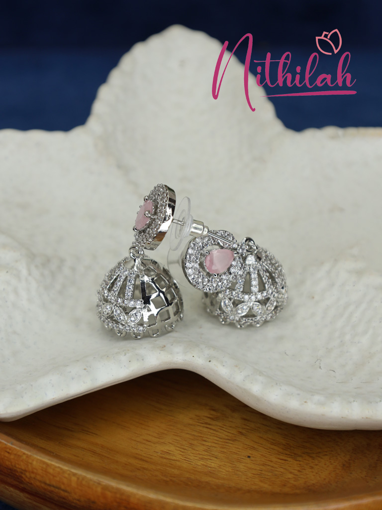Close-up of silver-tone pink AD jhumka earrings showing pale pink teardrop stones, intricate dome detailing, and push-back earring posts.